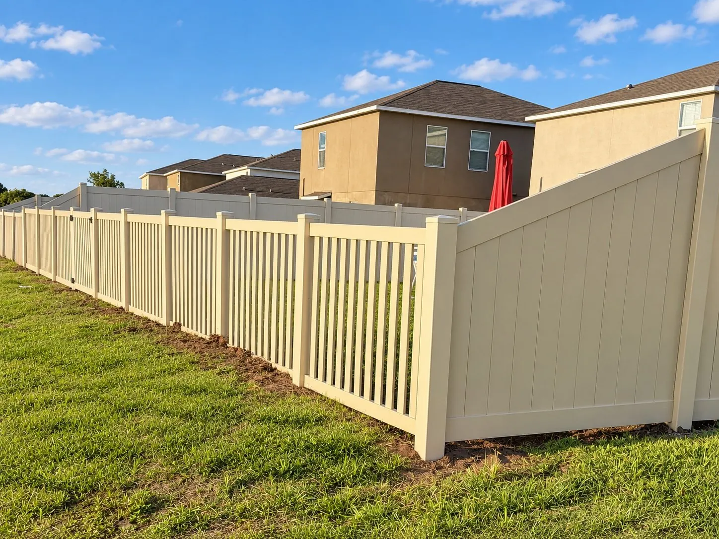 Beige vinyl fence with a picket section under a blue sky